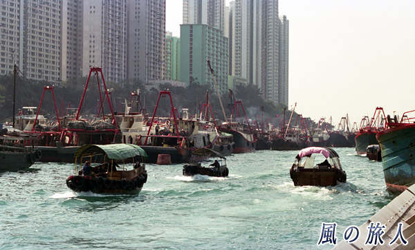 香港仔を行き交うサンパン船とビル群の写真