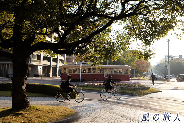 路面電車と自転車をこぐ女学生の写真